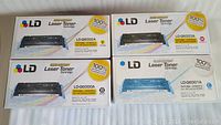 Four laser toner cartridges in original packaging, colors include black, yellow, magenta, cyan