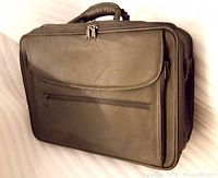 Front view of black leather briefcase showing main compartment zippers, top handle, and front zippered pocket.