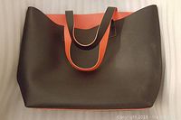 Brown casual handbag with orange inner lining and handles shown from front view.