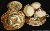Five-piece ultra thin China tea set shown on dark background featuring teacups, saucers, bowl and plate with intricate floral and geometric designs.