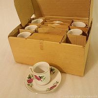 Six mini tea or espresso cups with matching saucers packed inside a cardboard box.