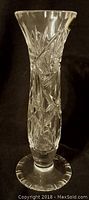 Small clear crystal flower vase with cut leaf and floral designs, flared top and circular base.