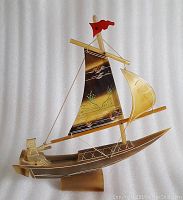 Photo of water buffalo horn traditional Chinese fishing boat with detailed painted sail, miniature figure rowing, and red flag.