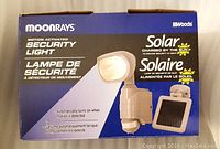 Box front of Moonrays motion activated solar security light showing product details and solar charging feature.