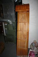 Full view of wooden toboggan showing length and design, positioned vertically against wall.