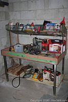 Full view of metal utility cabinet and items on top rack and middle shelf including paint supplies, tools, automotive fluids.