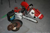 Both Stihl tools with oil container and stack of abrasive blades on concrete floor
