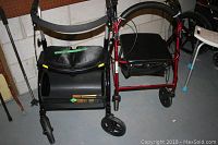 Two walkers side by side; black Espresso Lite Walker on left and red Formedica Walker on right with padded seats and storage compartments