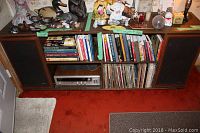Front view of the cabinet with stereo receiver, speakers, vinyl records and books.