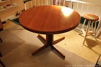 Overall view of round teak tabletop and pedestal base from front left angle