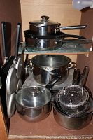 Photo of stacked stainless steel pots with lids, cast iron frying pan, and steam basket.
