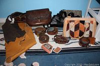 Group photo showing 5 purses, 5 belts and 2 fabric pieces arranged on the floor with a blue wall background.