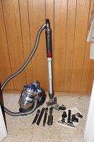 Full view of Dyson DC 20 canister vacuum with hose, telescoping wand, and multiple cleaning attachments laid out on floor