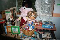 Full view of collection including two dolls, various boxed board games, and a basket with small toys.