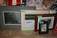 Four framed art prints arranged side-by-side on carpeted floor showing full view of items