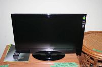 Insignia 24-inch LCD TV/DVD unit on wooden surface with remote and manuals nearby.