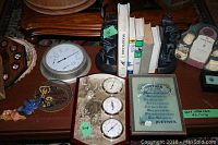 Photo showing totem book ends, books, barometers, and framed plaques on display.