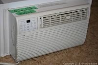 Kenmore white window air conditioner unit installed in window opening, showing front and side views.