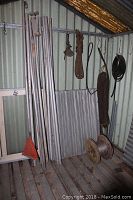 Corner of corrugated shed showing rods on left, mesh sheet behind and ropes hanging