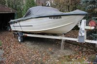 Side view of covered aluminum boat on single-axle trailer