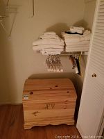 Custom made pine chest with arched lid labeled 645, seen from front with towels and hangers above it.