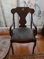 Front view of antique occasional chair showing dark wood frame, cutout back, upholstered seat.
