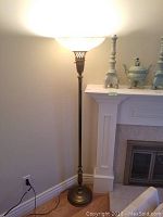 Full view of the lit floor lamp standing beside fireplace.