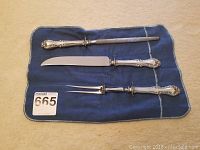 Overview of carving set on blue cloth including knife, fork, and sharpening steel