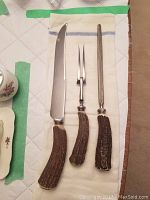 Full set including carving knife, fork, and sharpening steel with resin handles resembling antler texture.