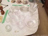 Overview of entire set arranged on white quilted surface showing bowls, dessert cups, plates, jewelry holder, and pitcher with ladle