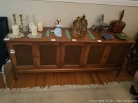 Full view of the sideboard showing four doors with cane inserts and decorative items on top.