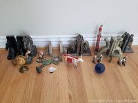 Photo showing all items including marble bookends, miniature globe, animal figurines, painted cow figurine, wooden and beaded dolls, and small sculptures arranged on floor.