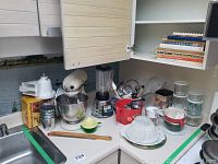 Wide view of countertop showing mixer, attachments, blender, utensils, bowls, canisters and cookbooks
