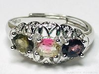 Close-up photo of the sterling silver ring showing three round tourmaline stones in green, pink, and deep purple under bright lighting.
