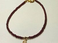 Full view of the rhodolite garnet bracelet showing the beads, gold plated charm and clasp.