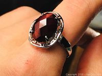 Close-up of the red tiger eye stone set in 925 sterling silver adjustable ring on finger, showing the faceted stone and prong setting.