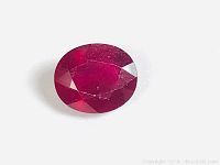 Close-up front view of oval blood red citrine gemstone showing facets and color depth.
