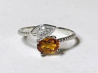 Close-up of the sterling silver ring showing the oval orange gemstone and CZ leaf.