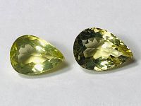 Two faceted pear-shaped lemon citrines placed side by side on a white background, showing color and cut of the gemstones.