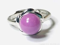 Close-up photo showing polished silver ring with round cabochon purple Arizona Micah stone in a flower-like setting.