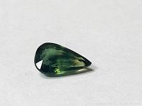 Single pear shaped green sapphire showing color and facets, size around 8x5 mm