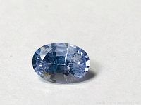 Close-up image of an oval-cut blue sapphire gemstone showing facets and color.