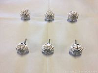 Top view of 6 hand painted brown and white ceramic knobs arranged in two rows on a flat surface.