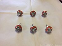 Top view showing 6 handcrafted ceramic knobs arranged in two rows, displaying detailed floral designs