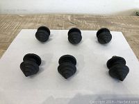 Photo showing all six black iron arrow-shaped knobs arranged on a white surface, front view.