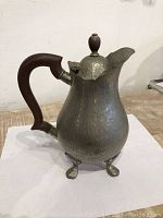 Front and side view showing the wooden handle and broken leg of the antique hammered metal silver tea pot.