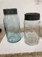 Two Crown Imperial glass jars, one clear and one light blue tinted, both with metal screw lids.