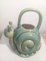 Side view of ceramic snail watering can showing shell and handle