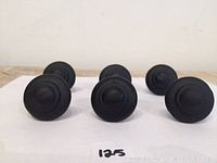 View from front showing six round iron knobs with concave circular design on face.