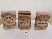 Three bars of handmade soap with visible labels for Black Raspberry Vanilla Cocoa Butter Soap, French Vanilla Oatmeal Soap, and Lovespell Goat's Milk Soap.